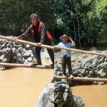 Lancur Susanto saat mencoba melintasi sungai dengan sebatang bambu.